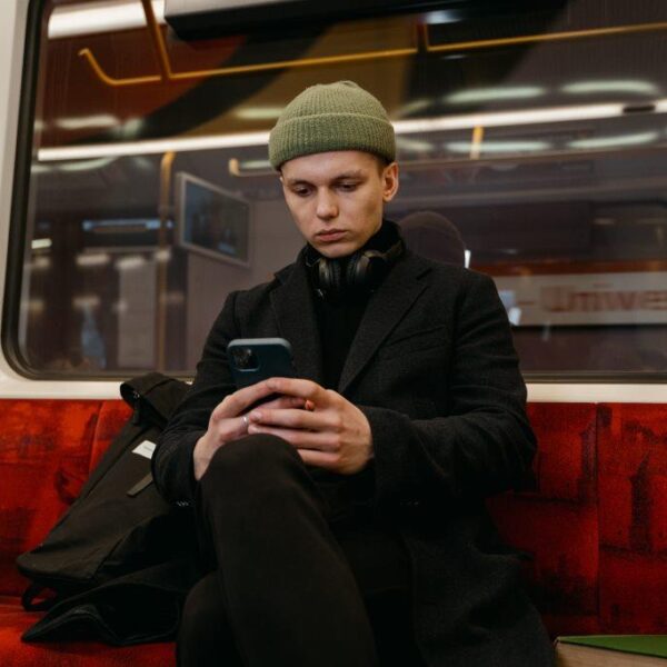 A well dressed, possibly European person on a metro train working on mobile phone, using public Wi-Fi networks