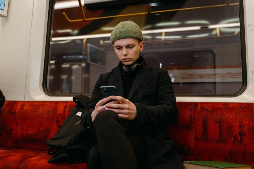 A well dressed, possibly European person on a metro train working on mobile phone, using public Wi-Fi networks